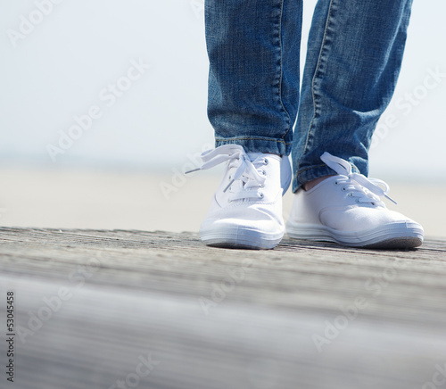Woman outdoors in blue jeans and comfortable white shoes