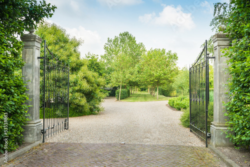 Opened black wrought iron gate of a large estate