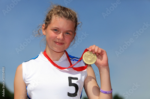 Uśmiechnięta dziewczyna ze złotym medalem.
