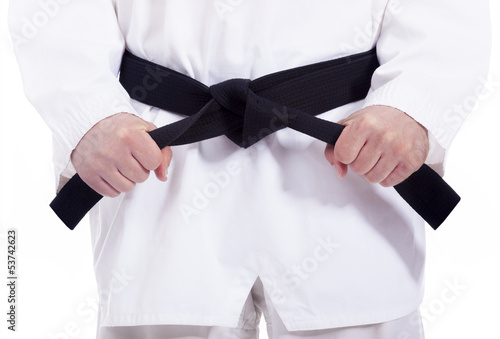 Martial arts man tying his black belt, isolated on white