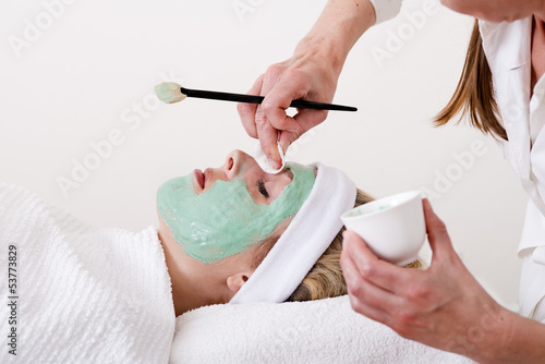 Beautician retouching a blond woman thalasso facial mask.