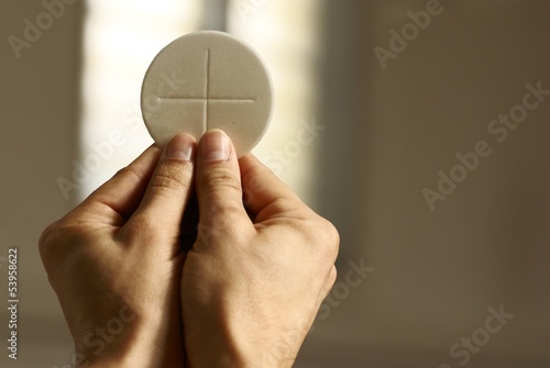 Hands holding communion wafer at church interior.
