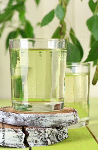 Glasses of birch sap on green wooden table