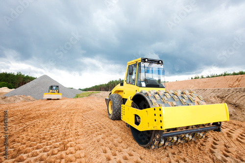 Soil compactor and bulldozer during road construction works