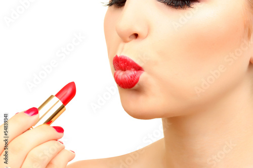 beautiful woman is applying her lips with red lipstick