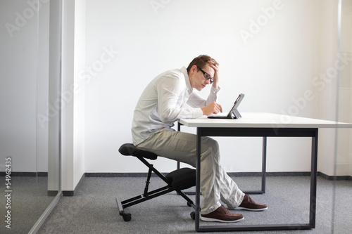 bad sitting posture at workstation. man on kneeling chair