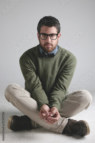 Modern man wearing black bowtie sitting on floor.