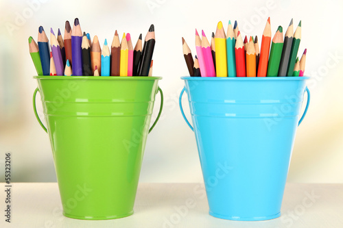 Color buckets with multicolor pencils, on color background