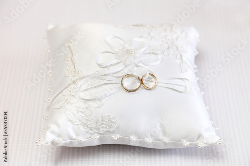 Obrączki ślubne na białej ozdobnej poduszce.