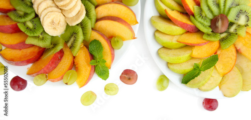 Assortment of sliced fruits on plates, isolated on white