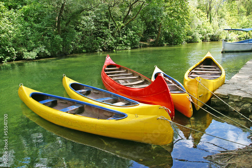 Five empty plastic canoes in turquoise green river