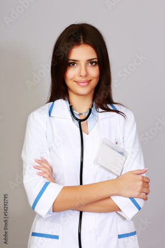 Beautiful young happy doctor over grey background