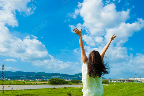 青空に向かって手を広げる一人の女性