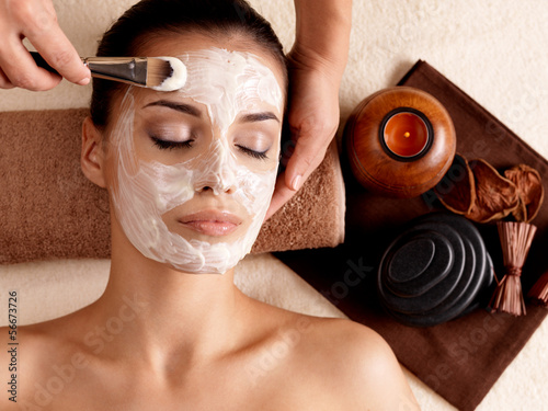 Spa therapy for woman receiving facial mask