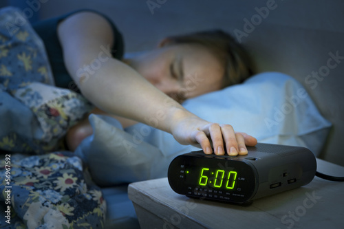 Woman waking up early with alarm clock