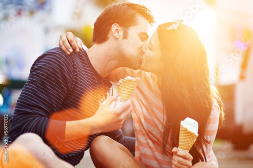 romantic couple kissing while holding ice cream