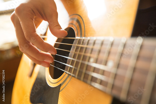 Female hand playing on acoustic guitar. Close-up.