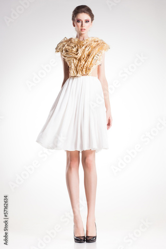 beautiful woman model posing in elegant gold and white dress
