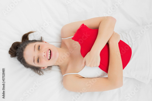 Smiling woman lying with a hot water bottle in bed