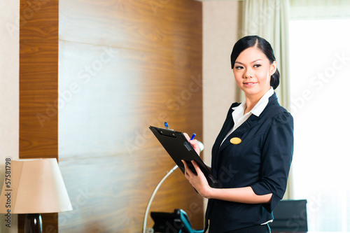 Asian executive housekeeper controlling hotel room