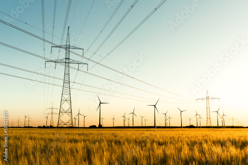 Strommasten, Kornfeld und Windräder im herbstlichen Gegenlicht