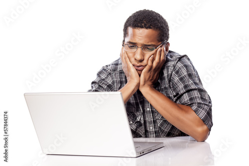 tired and sleepy dark-skinned man looking at his laptop