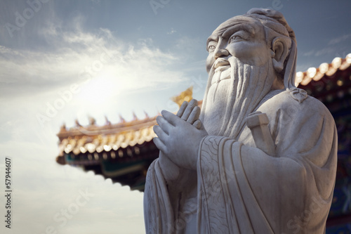 Close-up of stone statue of Confucius, pagoda roof in the background