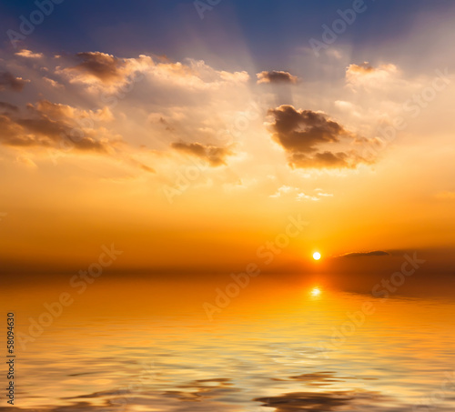 Beautiful sunset with clouds reflected in water.