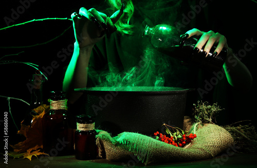 Witch in scary Halloween laboratory on dark color background