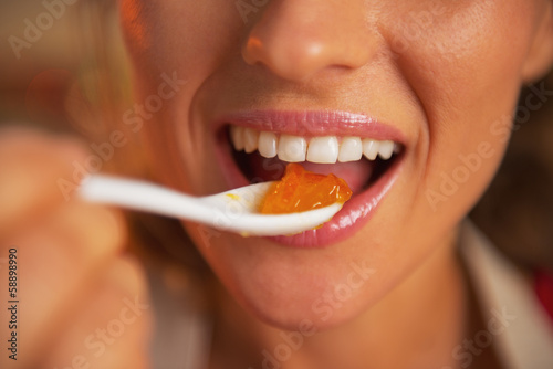 Closeup on happy young woman eating orange jam