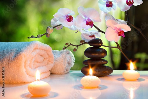massage composition spa with candles, orchids, stones in garden