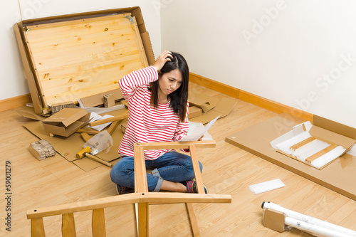 Asian woman assembling new chair with instruction
