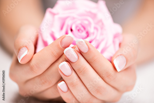 Beautiful woman's nails with french manicure and rose