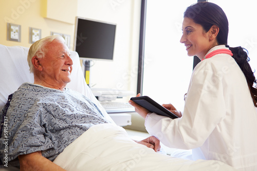 Doctor With Digital Tablet Talking To Patient In Hospital