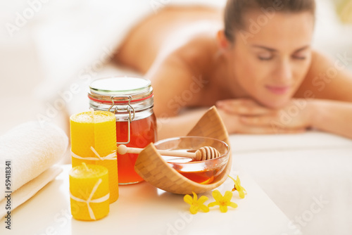 Closeup on honey spa therapy ingredients and woman in background