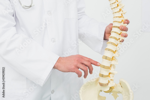 Mid section of a male doctor with skeleton model