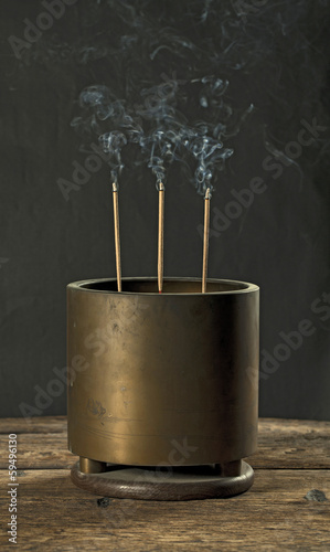 Antique incense burner on wooden table in dark background (Still