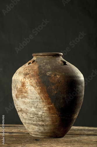 Antique ceramic jar on wooden table in dark background (Still li