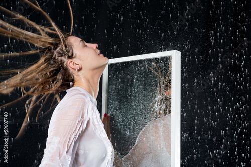 girl with disheveled hair under spray of water near mirror