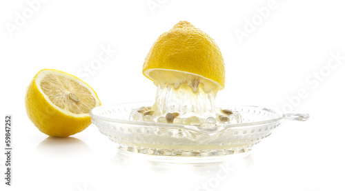 Glass citrus squeezer with lemons and juice on a white backgroun