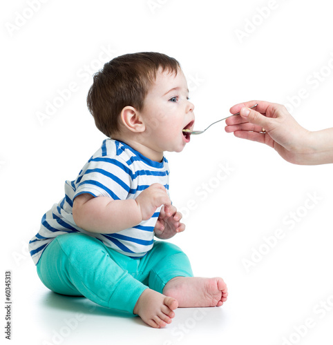 Mother's hand feeding baby with a spoon