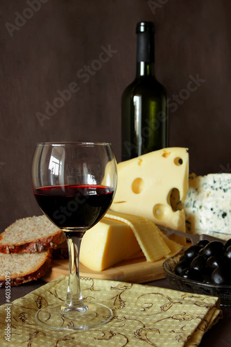 Glass of red wine, and several varieties of cheese