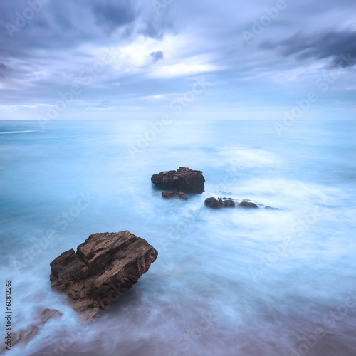 Rocks in a ocean waves under cloudy sky. Bad weather.