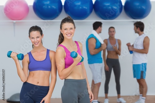 Fit women holding dumbbells with class in background