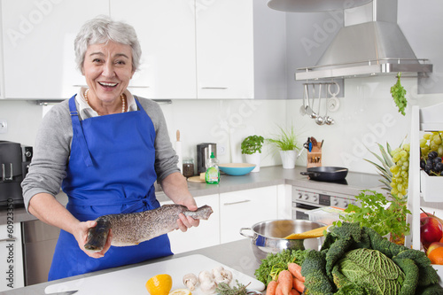 Frau bereitet Fisch in der Küche zu - Seniorin mit Hecht