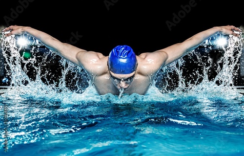Muscular young man in blue cap in swimming pool