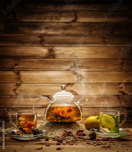 Teapot and glass cups with tea against wooden background