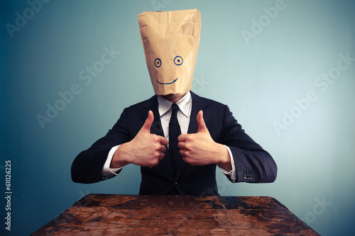 Businessman with bag over head giving thumbs up