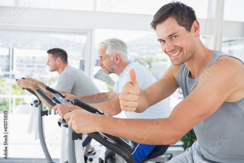 Man on exercise bike gesturing thumbs up