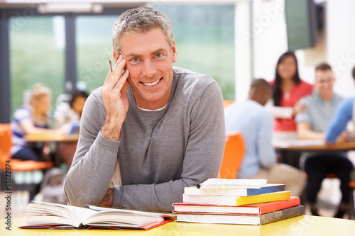 Male Mature Student Studying In Classroom With Books